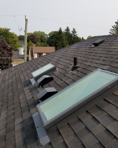 An image of a roof with new roof shingles and skylights.