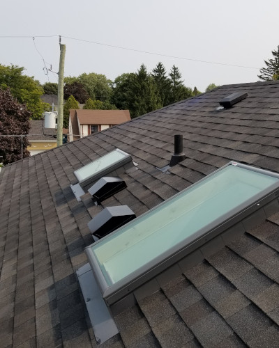 An image of a roof with new roof shingles and skylights.